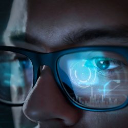 A SOC analyst's glasses reflecting data displayed on a a computer screen